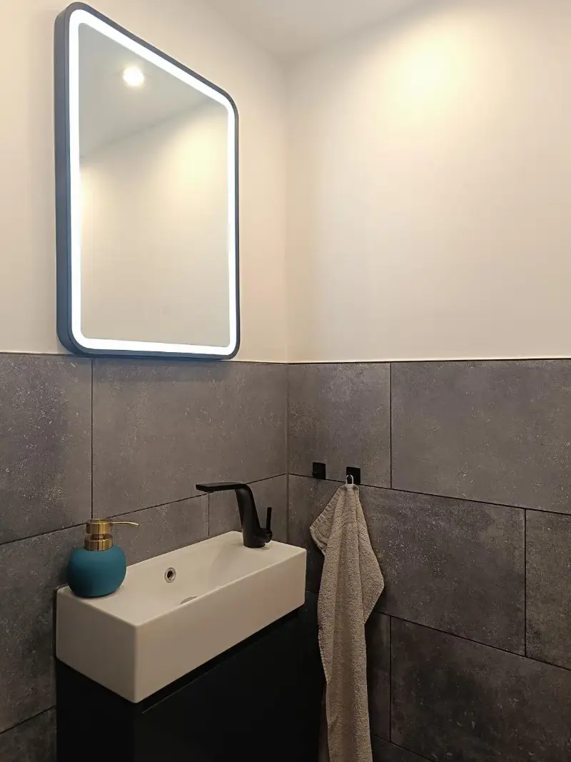 Gäste-WC mit Waschbecken und beleuchtetem Spiegel