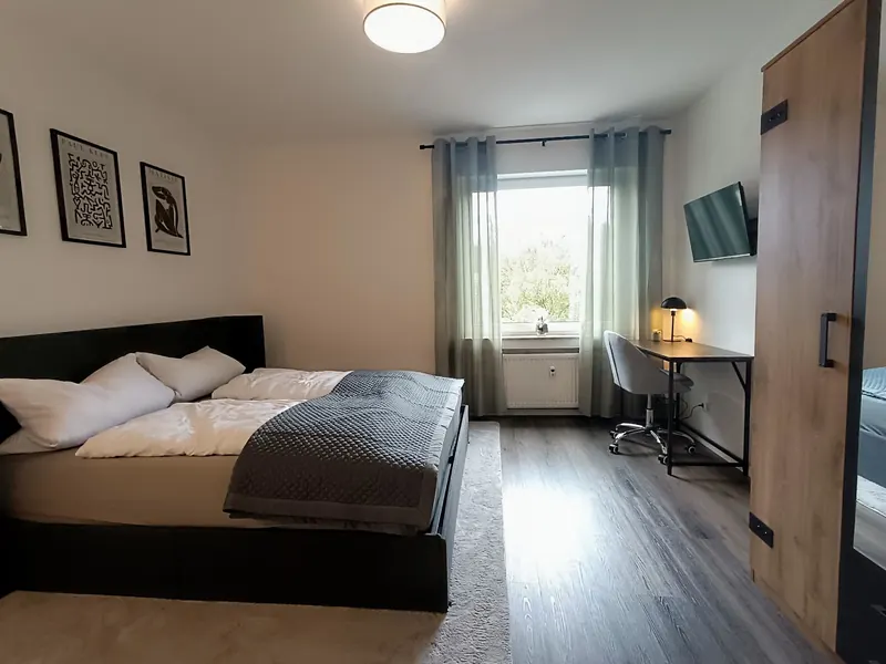 Schlafzimmer mit Doppelbett, Schreibtisch am Fenster und Wand-TV