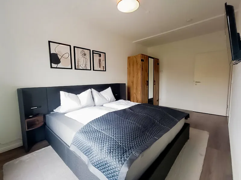 Schlafzimmer mit Polsterbett, Nachttischen und Eichenkleiderschrank