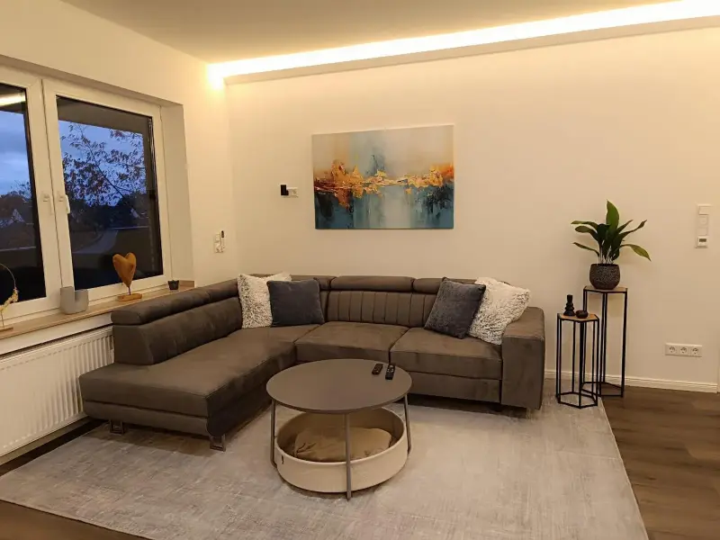 Wohnzimmer mit großem Ecksofa, Couchtisch und Pflanzen